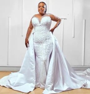 Elegant woman in a white, fitted gown with a long train.