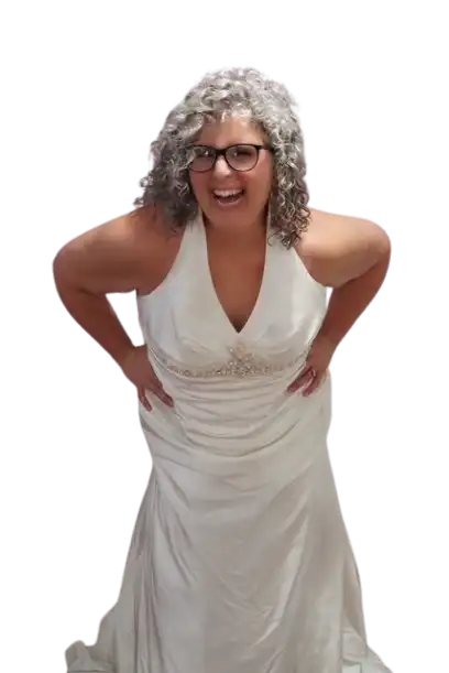 Smiling woman in a sleeveless white gown leaning forward playfully.