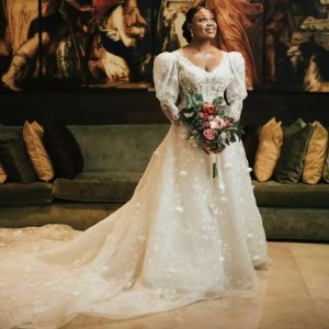 Bride in a white lace dress with puff sleeves holding flowers