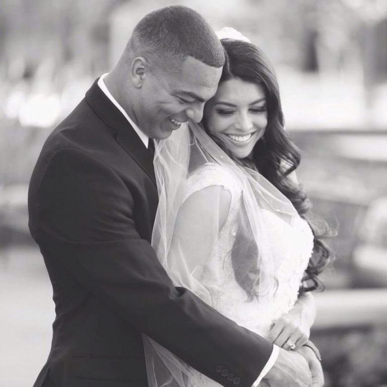 A smiling couple in wedding attire, sharing a loving embrace.