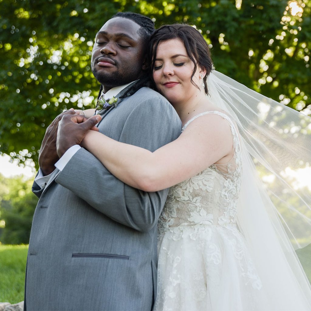 A couple embracing, with the bride wearing a white dress and veil.